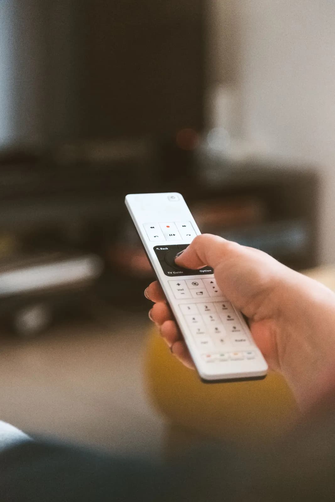 Close-up of a remote control in front of a television.