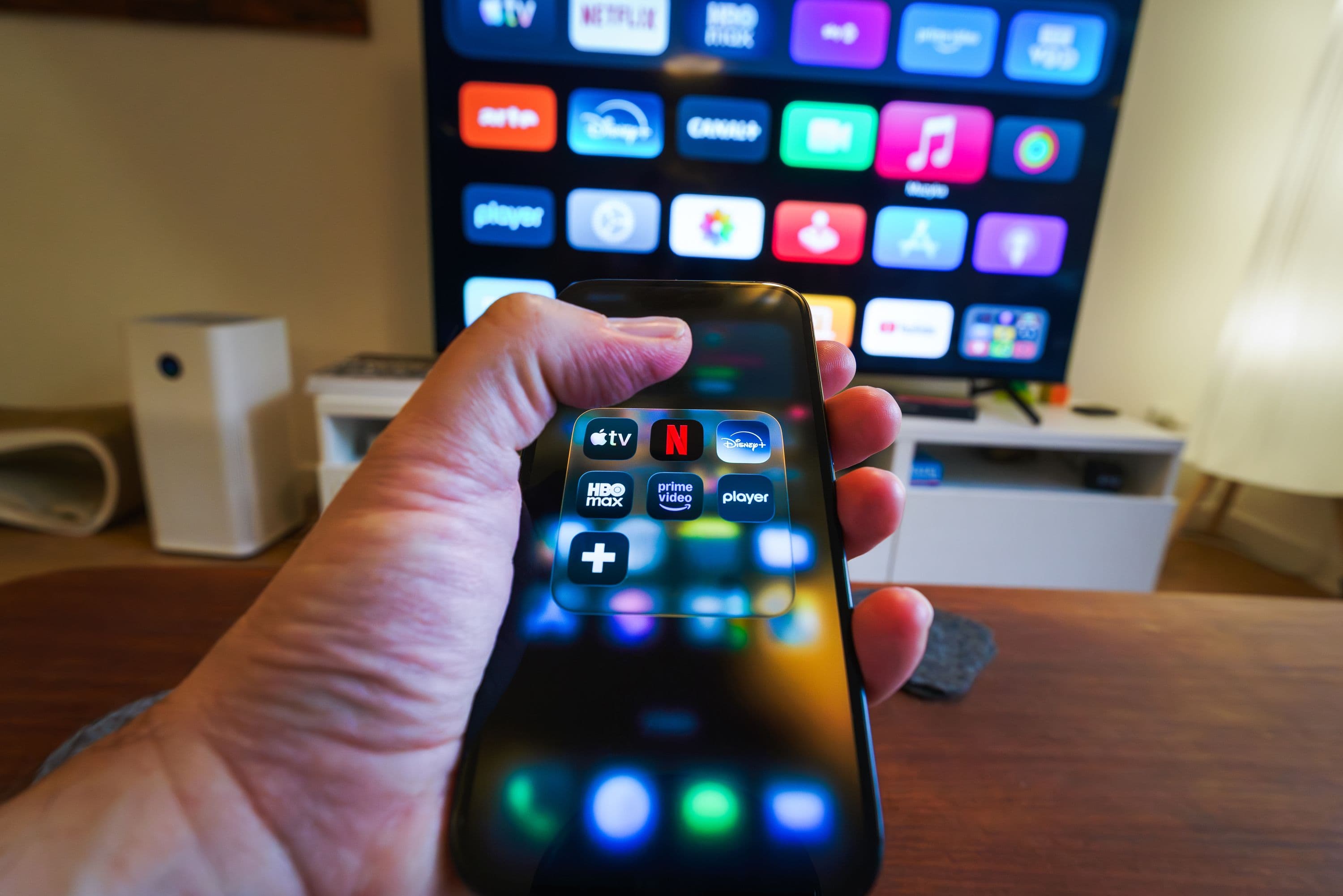Smartphone in front of a television showing streaming apps in a home setup.