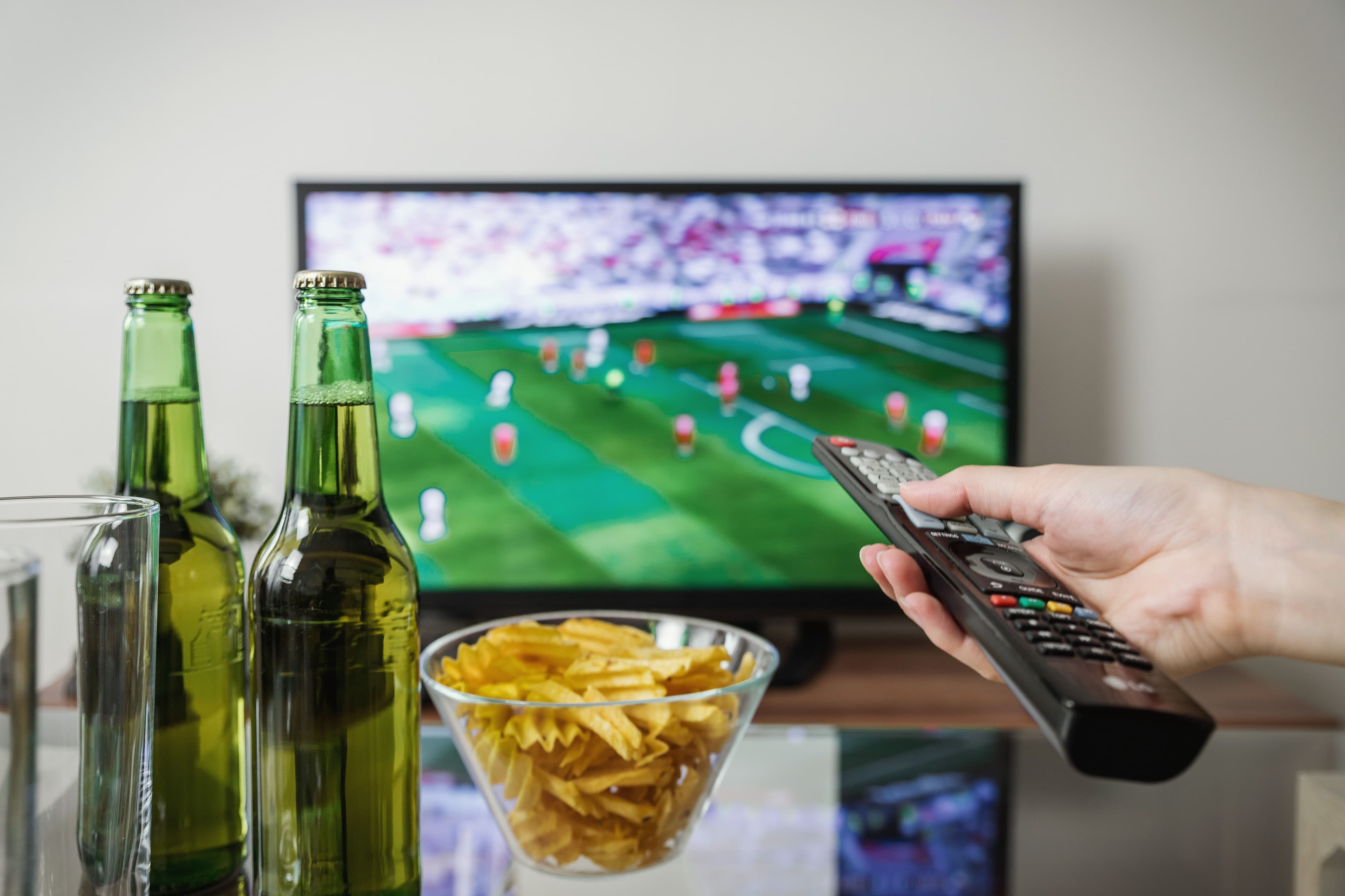 Remote control pointed toward a television during a live match at home.