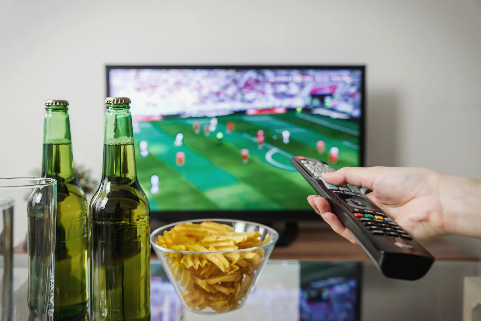 Remote control pointed toward a television during a live match at home.